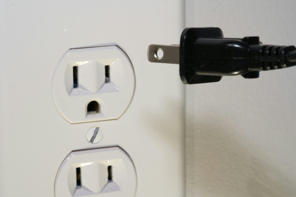 close up of cord being plugging into two prong outlet