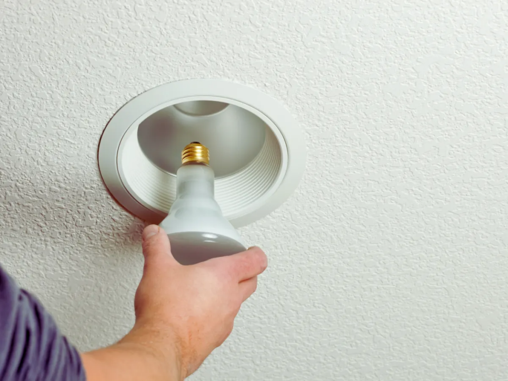 electrician replacing light bulb in recessed lighting