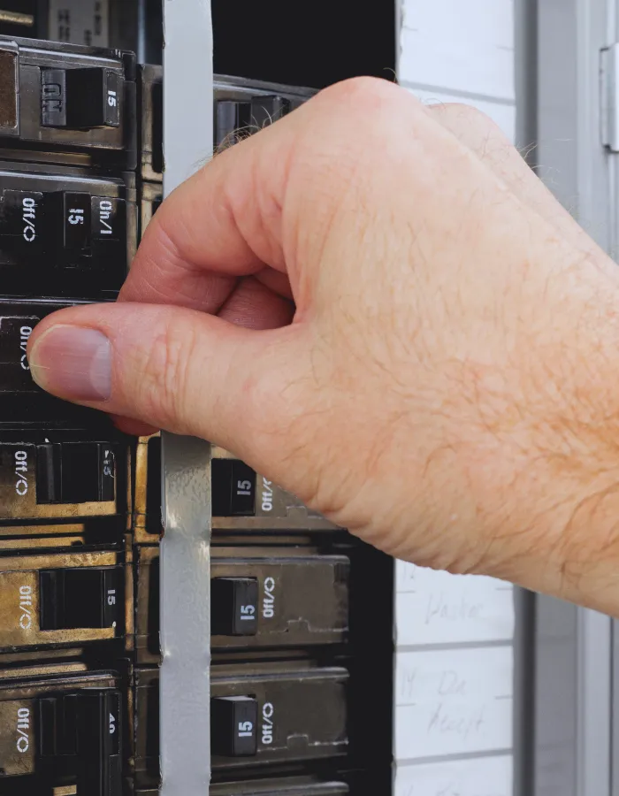 homeowner switching on tripped circuit breaker
